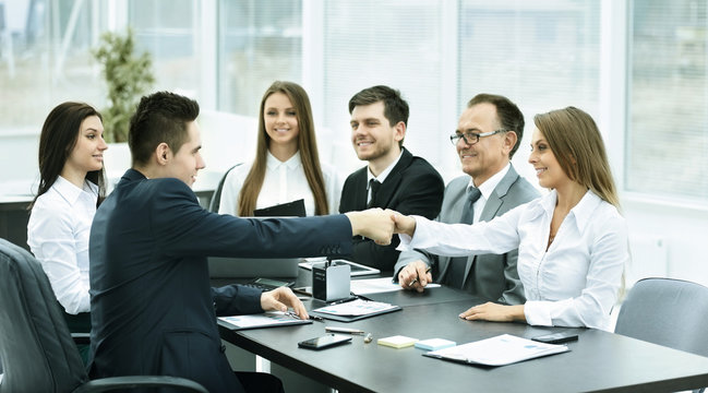 handshake business partners at a meeting in creative office on the background of business team