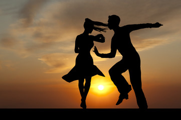 Silhouette couple in the active ballroom dance on sunset