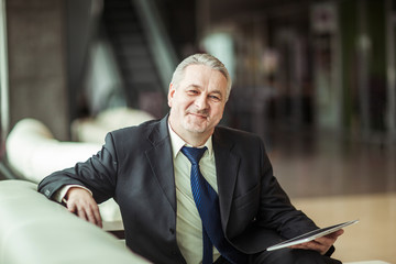 Fototapeta premium portrait of businessman with digital tablet sitting in the chair in front of the office.