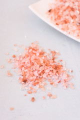 Pink Himalayan salt spilled on white table, spa, wellness, health concept