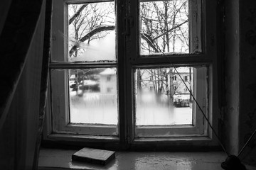 Fototapeta premium A wooden old window from which a winter courtyard is visible. Khabarovsk Krai settlement Vysokogorny March 2017