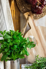 Provence style kitchen interior, white board wall, glass bottle, rattan coaster, linen towel, utensils, fresh pepper mint