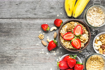 bowl of oatmeal muesli with strawberry, granola, banana and nuts
