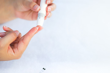 Asian woman hands using lancet on finger to check blood sugar test level by Glucose meter, Healthcare Medical and Check up, Medicine, diabetes, glycemia, health care and people concept