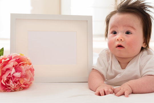 Happy baby boy with photo frame and flower