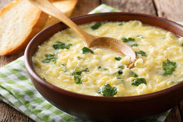 Italian egg cream soup stracciatella with farfalline pasta and cheese close-up. horizontal