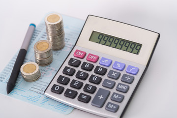 Increasing columns of coins, piles of coins arranged as a graph and calculator with pen on white background