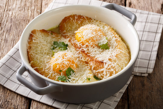Baked Pawese soup with toast, eggs and parmesan in a saucepan. Horizontal
