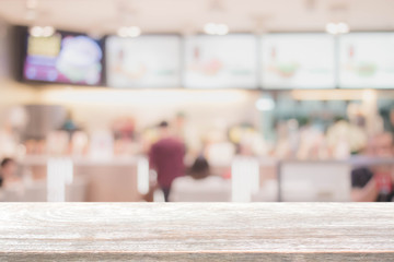 Wood table top and blurred restaurant interior background with vintage filter - can used for display or montage your products.