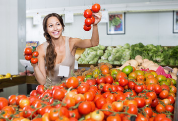 Woman customer holding ripe tomatoes on supermarket