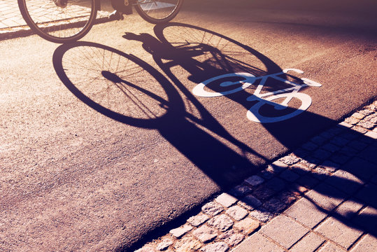 Fototapeta Shadow of unrecognizable cyclist on bicycle lane