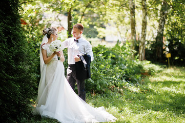 Stylish and gorgeous wedding couple walking outdoor at park on sunny weather.