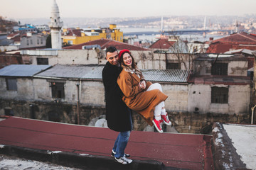 Funny stylish couple having fun on roof. Red beret and beige coat