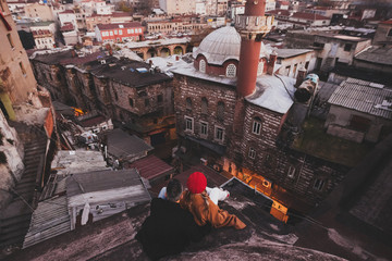 Couple in love sitting  on roof with view of evening Istanbul. Casual style, autumn look, red beret and beige coat