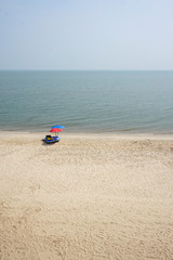 Fototapeta na wymiar red and blue parasols with inflatable boat on the clear beach