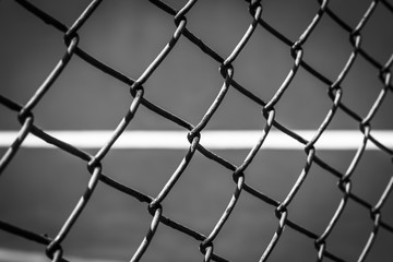 Close-up wire mesh steel with cort tennis background in black and white.