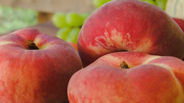 Close-up ripe a flat peach on background of a still-life of fresh fruit