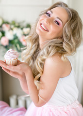 Beautiful blonde girl holding a cake in her hand and laughing