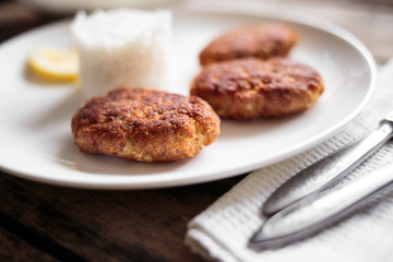 Three fish breadcrumbed cutlet on white plate with rice. Restaurant menu background