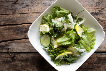 Fresh salad in white bowl on wooden background. Close up image of healthy food