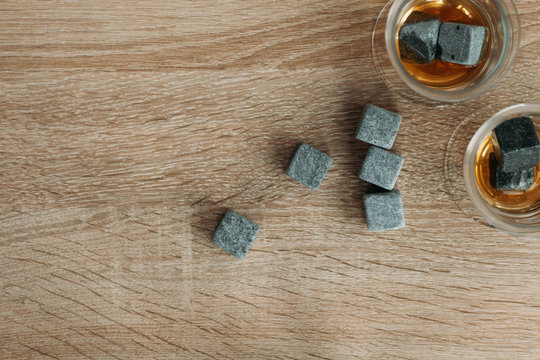 Stones for cooling whiskey and glases tulup on light wooden background