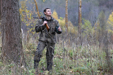 Fototapeta premium Man in camouflage and with guns in a forest belt on a spring hun