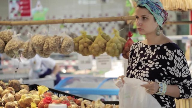Young attractive woman in a supermarket selects the fruits and vegetables.