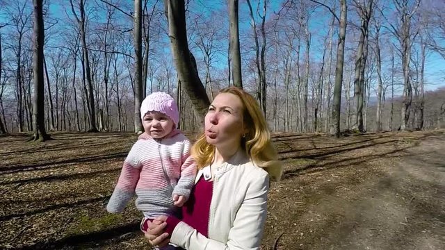 Slow motion of mother and baby girl walking in the park during a sunny day