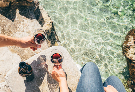 Fototapeta Close up image man and woman hands with goblet of wine at the sea side