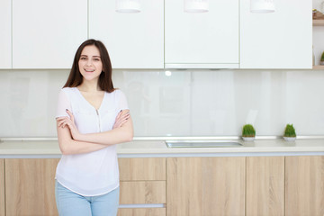 Pretty young woman With black hair standing in kitchen and smiling
