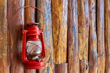 Red oil lamp hanging on wooden wall