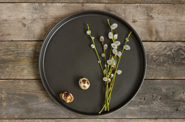 Two quail eggs on a plate with sprigs of willow