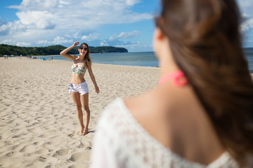 Fototapeta premium Happy girl standing on beach smiling to her friend