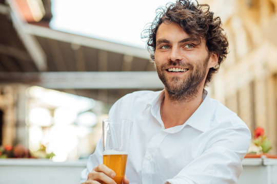 handsome elegant man sitting outside ar terrace drinking beer