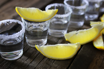 stack of tequila with salt and lemon on a wooden background