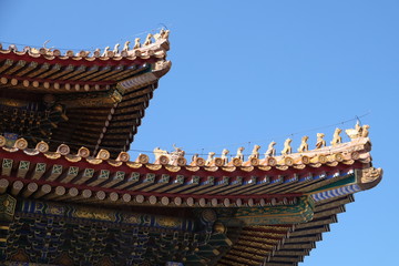 Fototapeta na wymiar Tiled roof and facade decorated with a Chinese pattern. Palace in The Forbidden City, Beijing, China