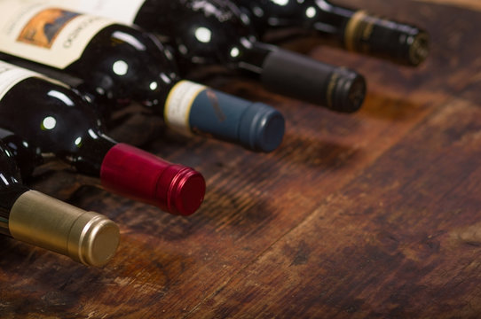 Row of wine bottles with dry red  wine on wooden background. Low depth of field. 