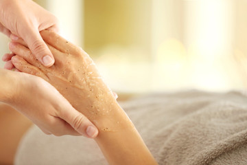 Hand of young woman having scrub treatment in beauty salon, close up view