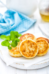 Cottage cheese fritters on white wooden background closeup