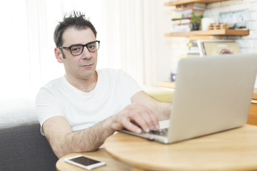 Man sitting in his living room and working on laptop. Morning scene