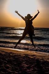 An attractive girl jumping happily out of the sunlit sea