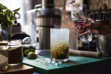 Bartender in a trendy hipster bar creates a fresh drink with sparkling water soda lime lemon and cane sugar in artisanal way