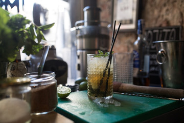 Side shot with selective focus of a refreshing summer mixed drink mojito made with fresh herbs and citrus on a messy bar 