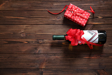 Decorated wine bottle and gift box on wooden background