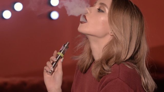 pretty girl vaper smoke e-cigarette in a nightclub