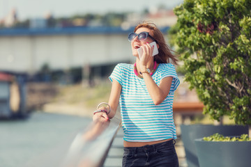 Girl using cellphone on the pier near the river.