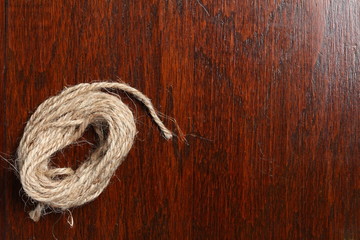 A coil of brown  manila  rope cable in normal light put on the  dark brown color hardwood gross...