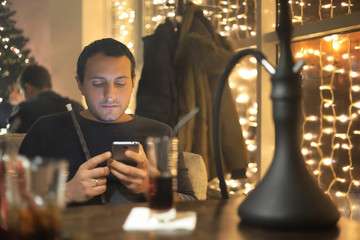 man smoking pipe of hookah in night cafe