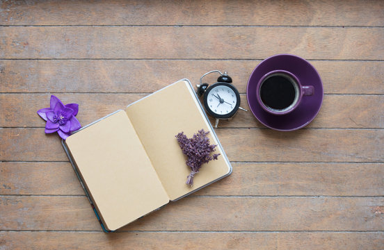 photo of opened notebook, bunch of lavender, purple flower, alarm clock and cup of coffee on the wonderful wooden brown background