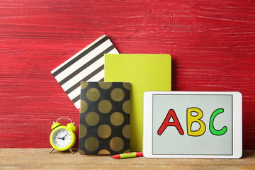 Tablet with ABC message and stationery on wooden table